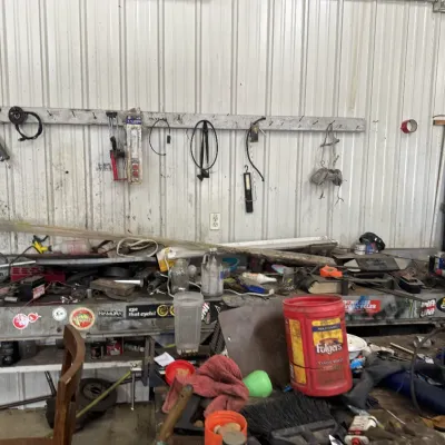 Sale Photo Thumbnail #63: Workshop area filled with various tools, hardware, and supplies on a long workbench and wall rack.