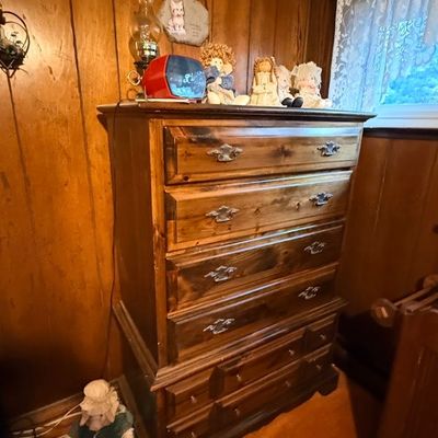 Rustic dark stain pine highboy chest of drawers with antique-style bale pulls, displayed alongside various decorative figurines.