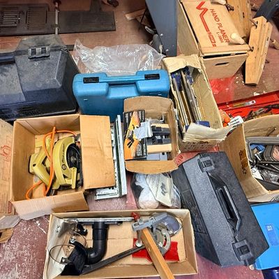 Collection of assorted power tools, hard plastic tool cases, C-clamps, and vintage woodworking accessories in cardboard boxes.