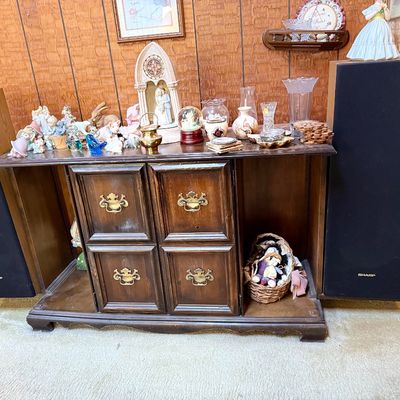 Traditional dark wood media console featuring a central cabinet, brass hardware, flanking Sharp floor speakers, and a tabletop displaying...