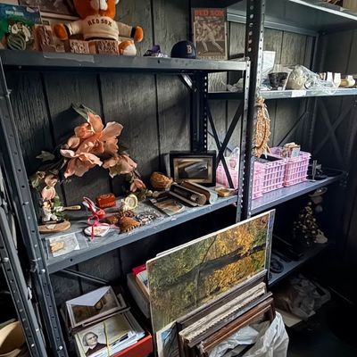 Metal shelving units filled with assorted collectibles, including Boston Red Sox memorabilia, framed artwork, artificial flowers, and...
