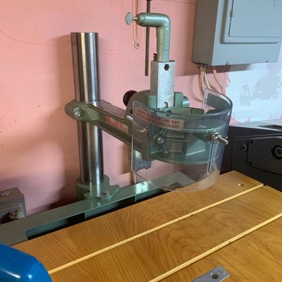 Vintage Shopsmith overarm router attachment with clear safety guard mounted on a wooden table.