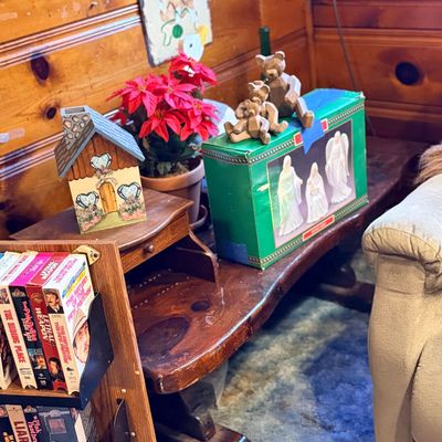 Rustic wooden coffee table with a small desk top section, holding decorative items including a house-shaped candle holder, artificial...