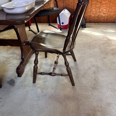 Vintage dark stained wooden Windsor-style dining chair paired with a matching trestle dining table displaying ceramic dishware.