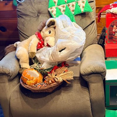 Plush stuffed horse, decorative pumpkin basket, and assorted holiday decor resting on a gray plush recliner chair.