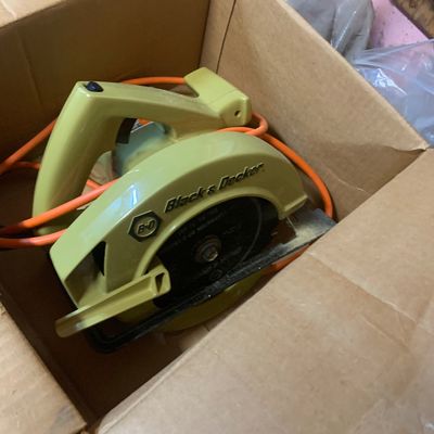 Vintage Black & Decker corded circular saw in avocado green, stored inside a cardboard box.