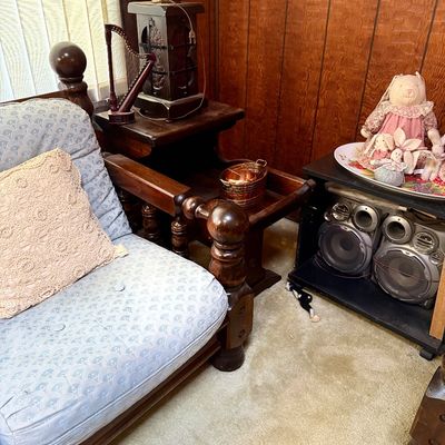 Vintage heavy dark wood armchair with light blue patterned cushions alongside a matching dark wood end table holding a lamp, miniature...