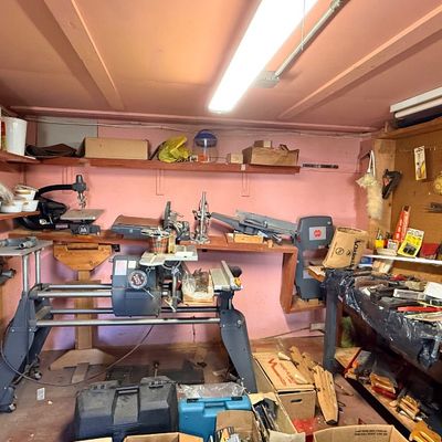Workshop room filled with power tools, including a Shopsmith multi-purpose woodworking machine, band saw, bench grinder, pegboard tool...
