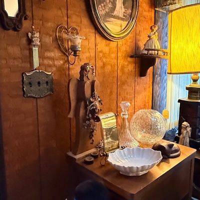Collection of vintage home decor including wall art, heart sconces, a wooden side table, glass decanter, crackle glass globe, and a large...