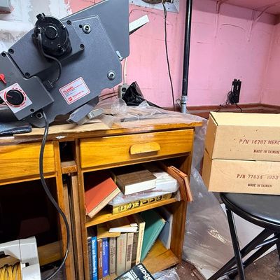 Vintage benchtop planer tool resting on a wooden desk alongside boxed model car kits and a Dremel drill press box.