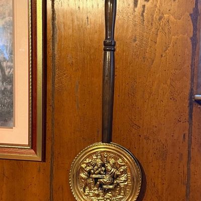 Vintage decorative brass bed warmer with a turned dark wooden handle and an embossed tavern scene on the lid.