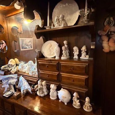 Vintage dark wood hutch and dresser filled with a collection of ceramic figurines, porcelain collectibles, glassware, and jewelry boxes.