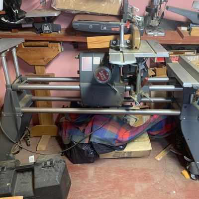 Vintage Shopsmith Mark V multi-purpose combination woodworking machine with table extensions, surrounded by various shop tools.