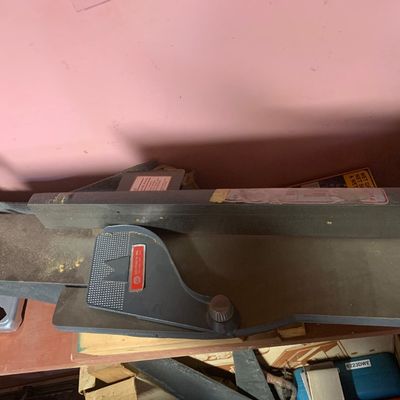 Shopsmith woodworking jointer attachment resting on a workbench, showing slight surface wear.