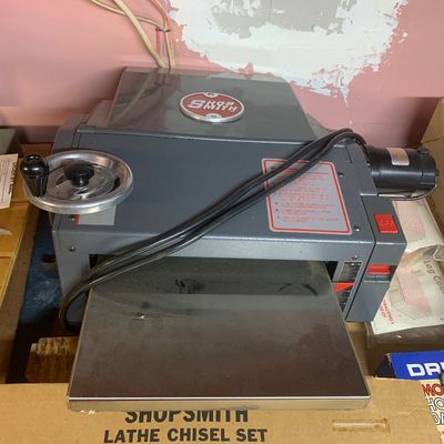 Shopsmith benchtop thickness planer tool sitting above a boxed Shopsmith lathe chisel set.
