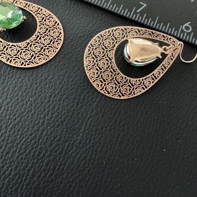 Sale Photo Thumbnail #149: Pair of gold-tone dangle drop earrings featuring a rose-patterned filigree teardrop design with center facetted peridot-green glass or crystal teardrops. Fitted with French wire hooks. Each earring measures approximately 2.25 inches in length. In good pre