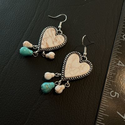 Sale Photo Thumbnail #168: Pair of Southwestern/Western style dangle hook earrings featuring heart-shaped central pendants with faux white/brown marble stone centers, textured silver-tone beaded borders, and dangling white and turquoise-colored bead charms. Good condition with no v