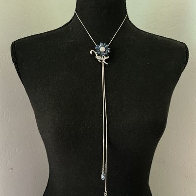 Sale Photo Thumbnail #162: Silver-tone lariat-style bolo necklace featuring a flower motif centerpiece set with marquise-cut navy/sapphire blue crystals and pavé rhinestones. Silver-tone snake chain ends with dangling blue rhinestone charm tips. Good pre-owned condition with no mi