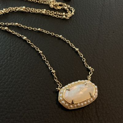 Sale Photo Thumbnail #175: Authentic Kendra Scott gold-tone pendant necklace featuring an oval iridescent Mother of Pearl style stone surrounded by a delicate seed pearl trim. Features the signature Kendra Scott filigree backing design, lobster clasp, and logo tag. In overall very 