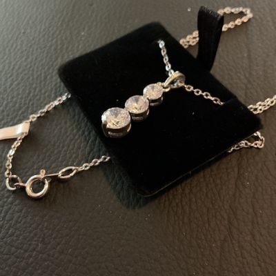 Sale Photo Thumbnail #193: Silver-tone chain necklace featuring a drop pendant set with three graduated round-cut clear cubic zirconia stones. Includes attached retail tag marked 'CZ PENDANT'. Fastens with a spring ring clasp. Comes displayed on a black velvet pad. Excellent condit
