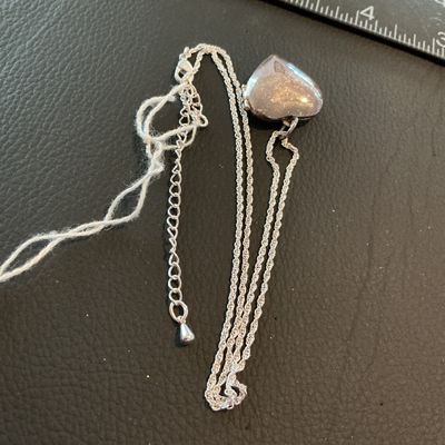 Sale Photo Thumbnail #226: A silver-tone rope chain necklace featuring a heart-shaped locket pendant. The front of the locket has a glittery enamel-style inlay bordered by clear rhinestones, and opens to reveal two picture slots. Includes an adjustable extender chain with a lobster