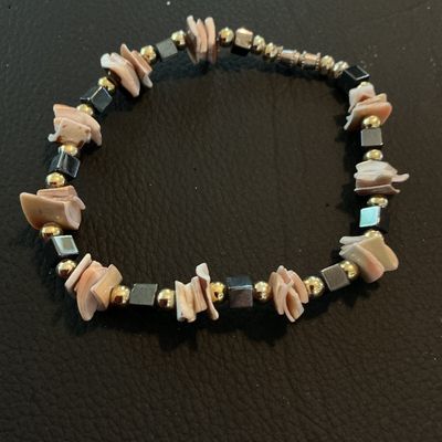 Sale Photo Thumbnail #198: Handcrafted-style beaded bracelet featuring natural sliced puka/heishe shell chips interspersed with metallic gold-tone round beads and dark metallic cube beads. Secured with a barrel twist clasp. Good pre-owned condition with no visible damage.