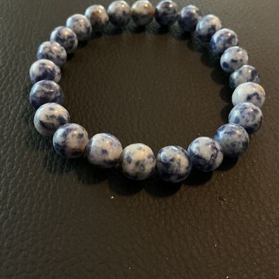Sale Photo Thumbnail #217: Beaded stretch bracelet featuring polished blue and white mottled stone beads (resembling sodalite or gemstone material). Good condition with no visible damage.