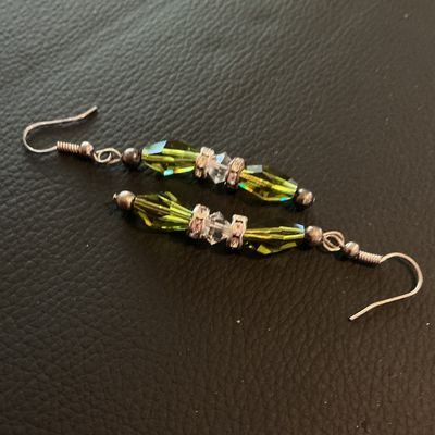 Sale Photo Thumbnail #213: Pair of dangle drop earrings featuring olive green elongated faceted glass beads accented with clear faceted crystal spacers and rhinestone rondelles on wire French hooks. Good condition with light metal patina.
