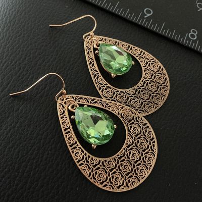 Sale Photo Thumbnail #148: Pair of gold-tone dangle drop earrings featuring a rose-patterned filigree teardrop design with center facetted peridot-green glass or crystal teardrops. Fitted with French wire hooks. Each earring measures approximately 2.25 inches in length. In good pre
