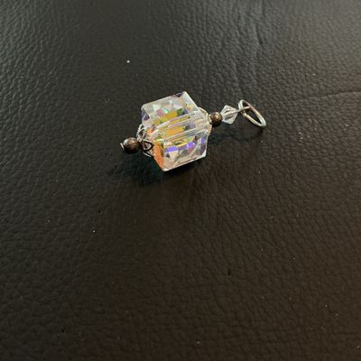 Sale Photo Thumbnail #203: Small pendant or charm featuring a cube-shaped faceted crystal with an iridescent aurora borealis coating. Accentuated with silver-tone decorative end caps, bead accents, and a top jump ring. Measures approximately 1 inch long including the ring. Good con