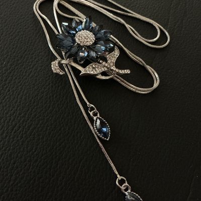 Sale Photo Thumbnail #163: Silver-tone lariat-style bolo necklace featuring a flower motif centerpiece set with marquise-cut navy/sapphire blue crystals and pavé rhinestones. Silver-tone snake chain ends with dangling blue rhinestone charm tips. Good pre-owned condition with no mi
