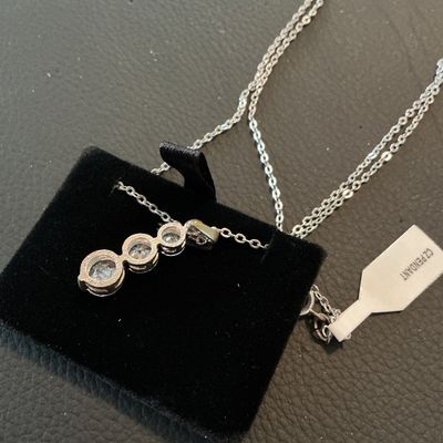 Sale Photo Thumbnail #195: Silver-tone chain necklace featuring a drop pendant set with three graduated round-cut clear cubic zirconia stones. Includes attached retail tag marked 'CZ PENDANT'. Fastens with a spring ring clasp. Comes displayed on a black velvet pad. Excellent condit