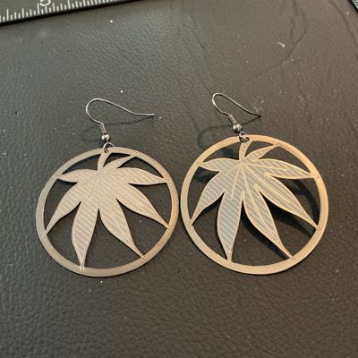 Sale Photo Thumbnail #186: Pair of circular drop dangle earrings featuring a textured cutout leaf design inside a round frame. Made of lightweight silver-tone metal with french wire ear hooks. Each circular drop measures approximately 1.75 inches in diameter. In good condition with