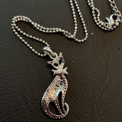 Sale Photo Thumbnail #202: Silver-tone ball chain necklace featuring a seated cat pendant encrusted with light blue rhinestones. Includes a lobster claw clasp with an extender chain. Good condition with all stones intact.