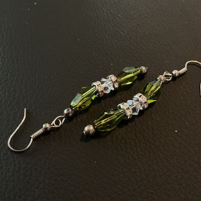 Sale Photo Thumbnail #214: Pair of dangle drop earrings featuring olive green elongated faceted glass beads accented with clear faceted crystal spacers and rhinestone rondelles on wire French hooks. Good condition with light metal patina.