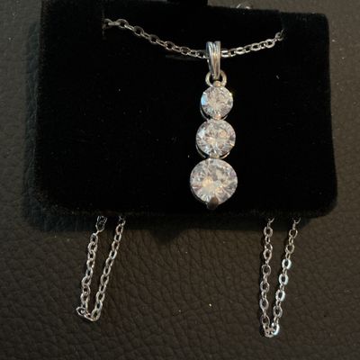 Sale Photo Thumbnail #192: Silver-tone chain necklace featuring a drop pendant set with three graduated round-cut clear cubic zirconia stones. Includes attached retail tag marked 'CZ PENDANT'. Fastens with a spring ring clasp. Comes displayed on a black velvet pad. Excellent condit