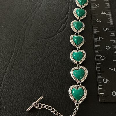 Sale Photo Thumbnail #126: Silver-tone link bracelet featuring six heart-shaped green stone or resin cabochons with faux turquoise veining, set in textured silver-tone heart borders. Finished with an adjustable toggle clasp and extension chain. Measures approximately 8 inches in to