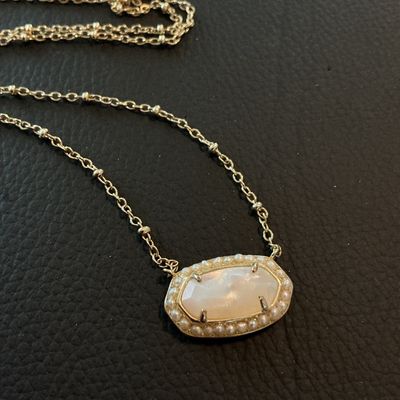 Sale Photo Thumbnail #174: Authentic Kendra Scott gold-tone pendant necklace featuring an oval iridescent Mother of Pearl style stone surrounded by a delicate seed pearl trim. Features the signature Kendra Scott filigree backing design, lobster clasp, and logo tag. In overall very 