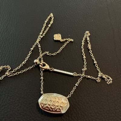 Sale Photo Thumbnail #176: Authentic Kendra Scott gold-tone pendant necklace featuring an oval iridescent Mother of Pearl style stone surrounded by a delicate seed pearl trim. Features the signature Kendra Scott filigree backing design, lobster clasp, and logo tag. In overall very 