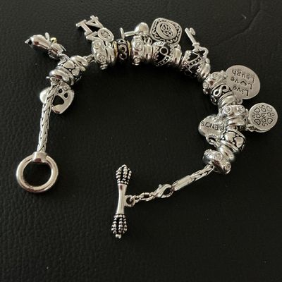 Sale Photo Thumbnail #166: Silver-tone charm bracelet with toggle closure featuring various charm pendants and decorative spacers. Charms include a paw print, "2014" date charm, wine glass, key, "Live Love Laugh" disc, "Friends" heart, and a faux turquoise stone drop. In very good 