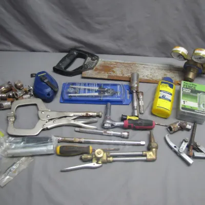 Sale Photo Thumbnail #260: Assorted vintage and modern hand tools, including locking C-clamp pliers, a hand saw, a torch head assembly, sockets, a chalk line reel, and a dual-gauge regulator.