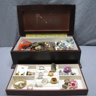 Sale Photo Thumbnail #116: Dark wood wooden jewelry box filled with various costume jewelry, including rings, bracelets, and statement pieces in a pull-out tray and top compartment.