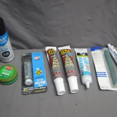 Sale Photo Thumbnail #177: Assortment of household adhesives, sealants, and spray paint, including Flex Glue, DAP caulk, epoxy putty sticks, 3M adhesive sealant, and O'Keeffe's Working Hands cream.