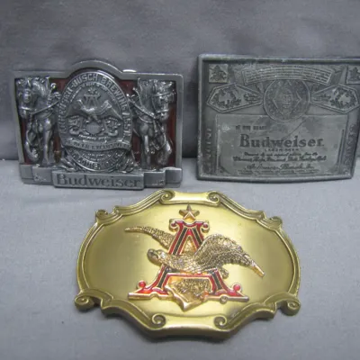 Sale Photo Thumbnail #279: Trio of vintage Budweiser brass and pewter belt buckles featuring classic Anheuser-Busch eagle and Clydesdale designs.