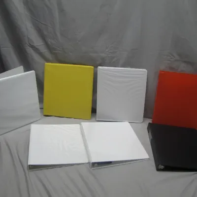 Sale Photo Thumbnail #239: Assortment of seven three-ring vinyl binders in white, yellow, orange, and black, appearing in good pre-owned condition.