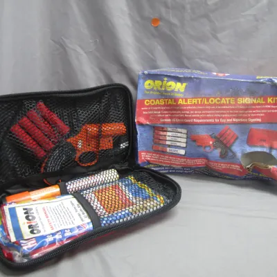 Sale Photo Thumbnail #30: Orion Coastal Alert/Locate Signal Kit including a flare gun, flares, and safety manual in a black zippered case alongside its damaged original retail box.