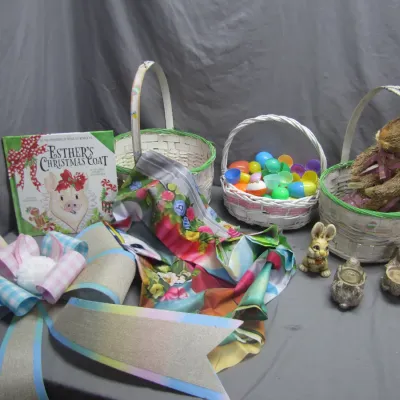 Sale Photo Thumbnail #131: Collection of Easter-themed decor including woven baskets, plastic eggs, a Sisal rabbit figurine, small rabbit statues, a floral table runner, a large burlap bow, and a children's book.
