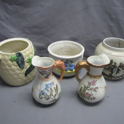 Sale Photo Thumbnail #94: Collection of five vintage ceramic pieces, including two small hand-painted floral pitchers, a pineapple-motif pot, and two decorative containers.