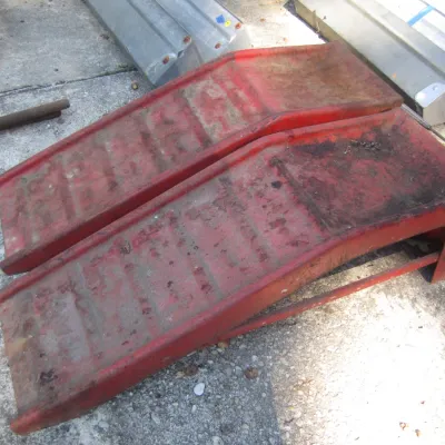 Sale Photo Thumbnail #142: Pair of heavy-duty red painted steel automotive service ramps showing surface rust and wear from use.