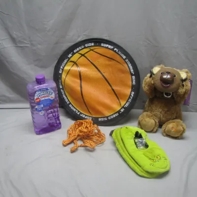 Sale Photo Thumbnail #240: Assortment of children's items including a brown teddy bear plush, green Grinch slippers, a large Fubbles bubble solution bottle, an orange replacement basketball net, and a basketball-themed super flying zoomer disc.